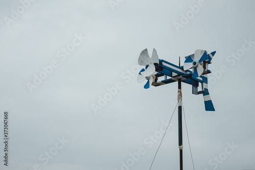 Horizontal shot of a weather vane with pinwheels and space for text photo