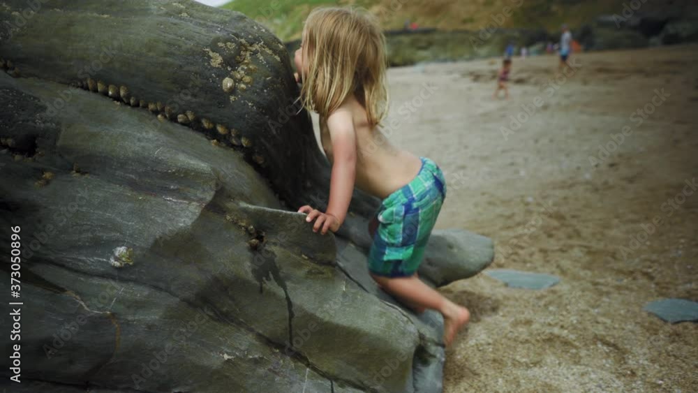 Preschooler climbing on rocks at the beach Preschooler climbing on rocks at the beach
