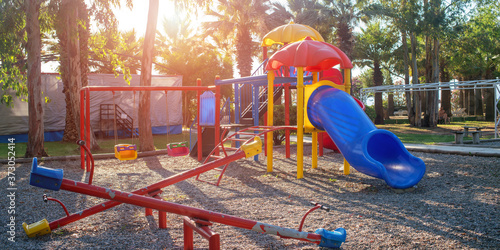 Принти на полотні children playground with colorful swing and plastic slide on sand in public park