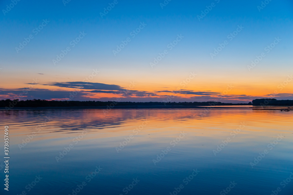 Fototapeta premium rays of the setting sun on the river bank