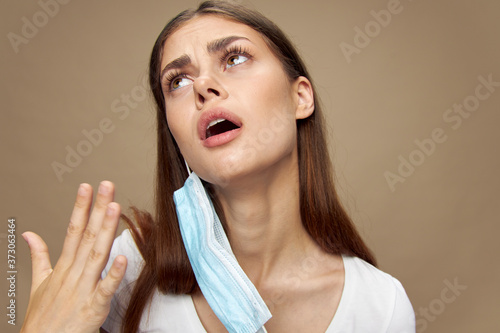 A girl in a medical mask and in a white T-shirt looks up and has an open mouth 