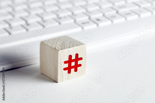 Hashtag symbol on a wooden cube with computer keyboard background on white