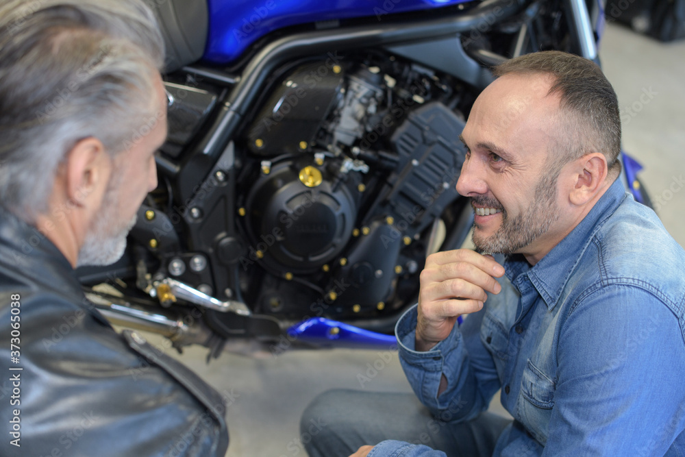 happy male mechanic with his client in garage happy male mechanic with his client in garage