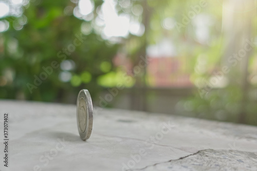 coins always have 2 side idiom idea concept, a Thai coin rolling on table with blurred background sunshine strong ligthing