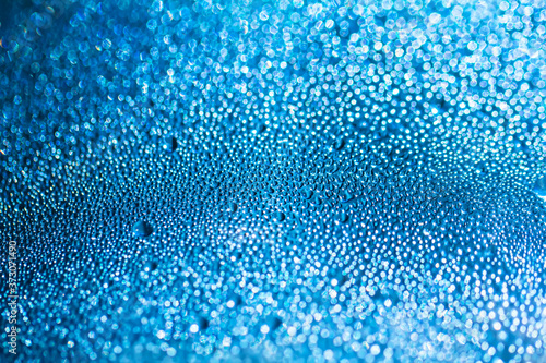 Blue water drops on the glass, abstract background, large and small drops. Space for text