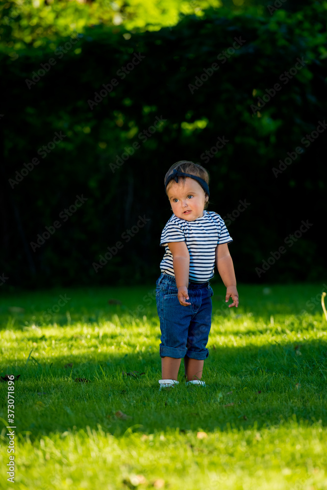 Baby girl walking on the lawn in the park. Baby girl walking on the lawn in the park.