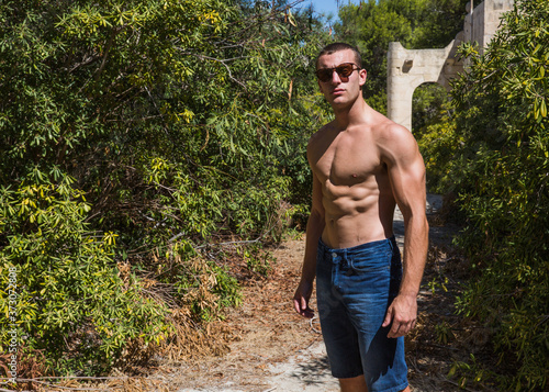 Young, muscular man standing outside an abandoned building