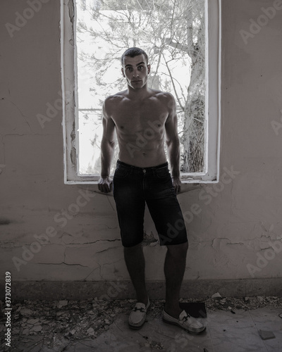 Young, muscular man standing in an abandoned building