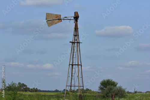 old broken windmill in the field with blue sky out in the country in Kansas.