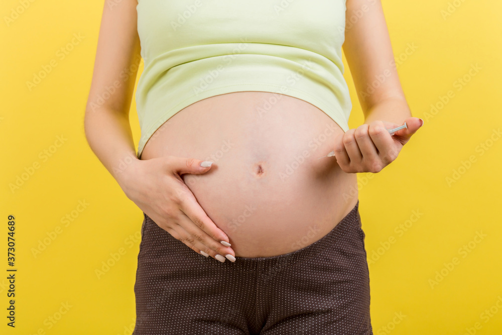 Cropped image of pregnant woman making insulin injection to control sugar level at colorful background with copy space. Healthcare concept Cropped image of pregnant woman making insulin injection to control sugar level at colorful background with copy space. Healthcare concept