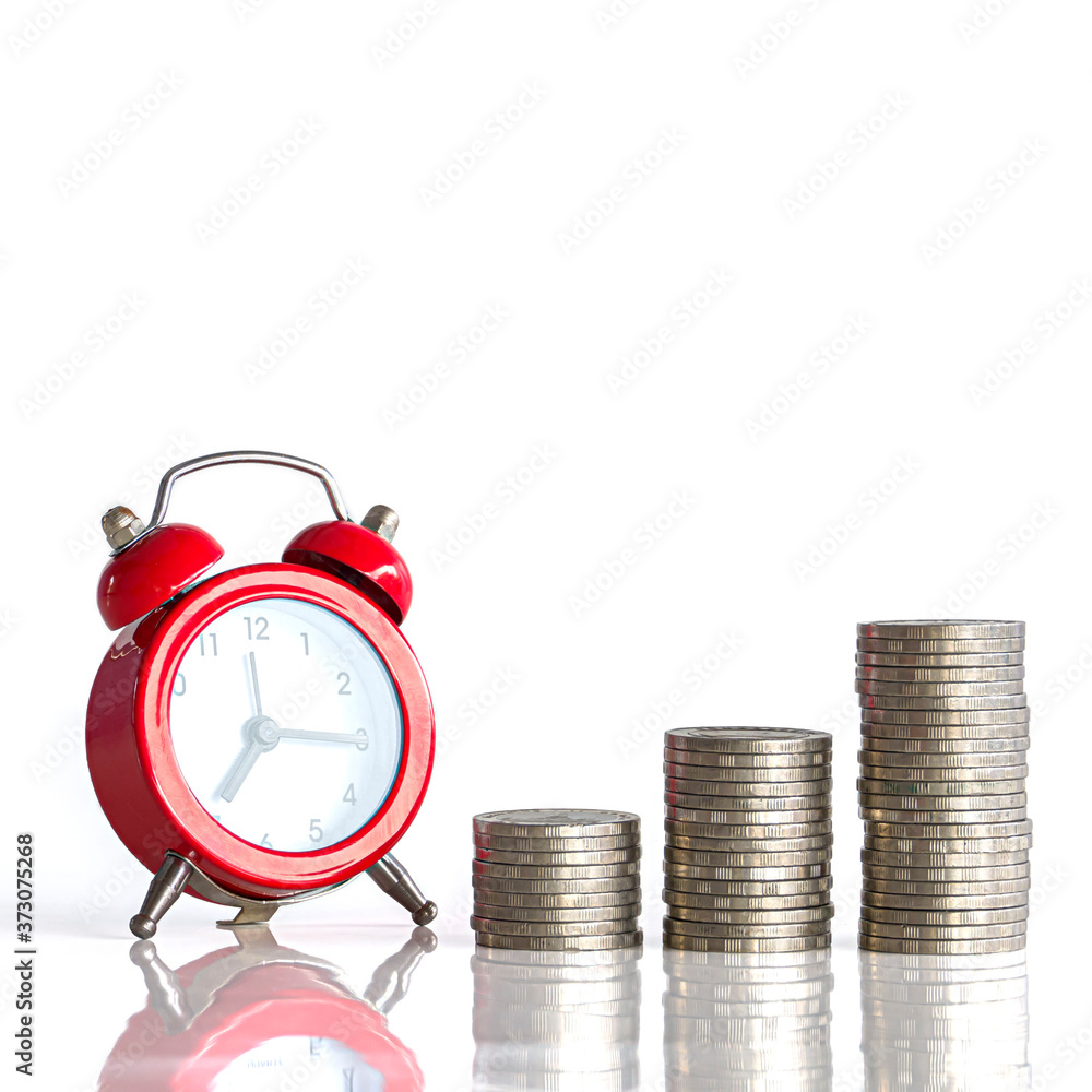 Close-up of a red clock and a pile of coins on a white background. Business Finance and Money concept. Save money to prepare for the future. Close-up of a red clock and a pile of coins on a white background. Business Finance and Money concept. Save money to prepare for the future.