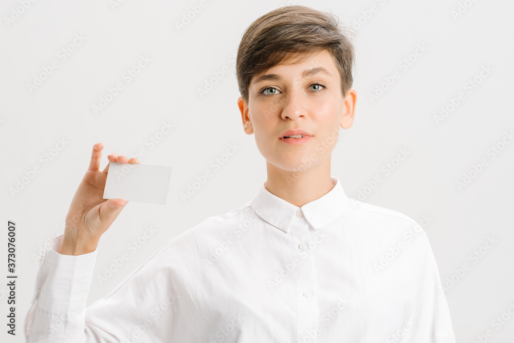 girl in a white office shirt holds out a business card. close portrait. girl in a white office shirt holds out a business card. close portrait.