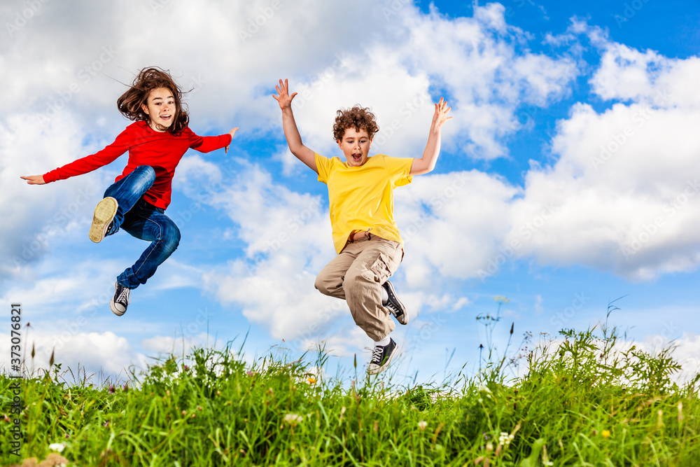 Girl and boy running, jumping against blue sky
Girl and boy running, jumping against blue sky