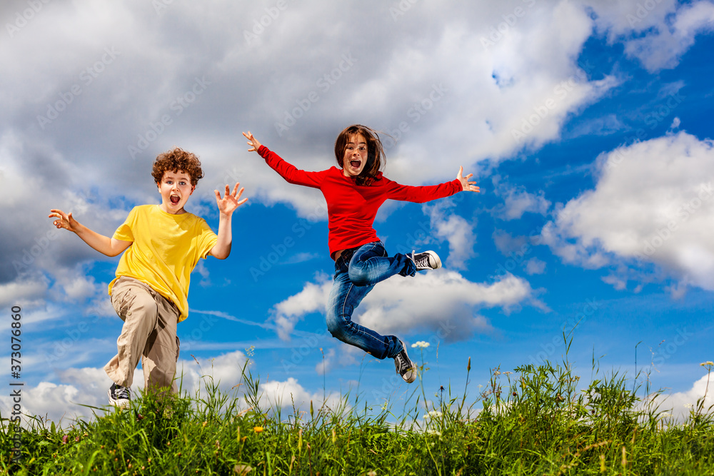 Girl and boy running, jumping against blue sky
Girl and boy running, jumping against blue sky