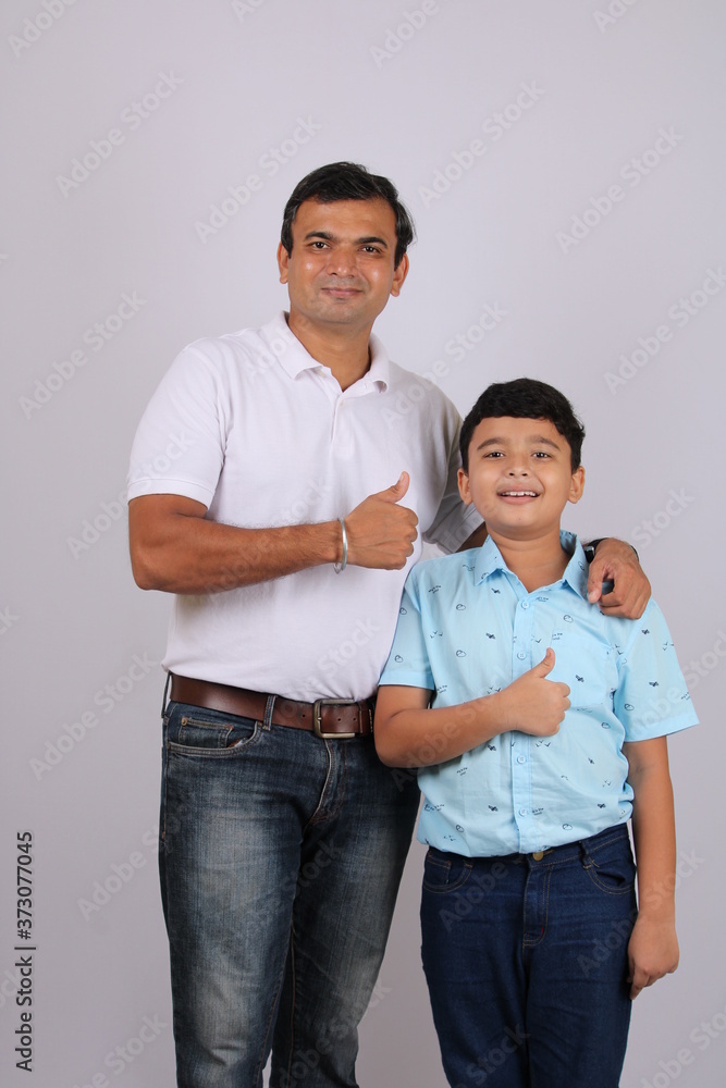 Young Indian Father and son giving thumbs up gesture over white background. Young Indian Father and son giving thumbs up gesture over white background.