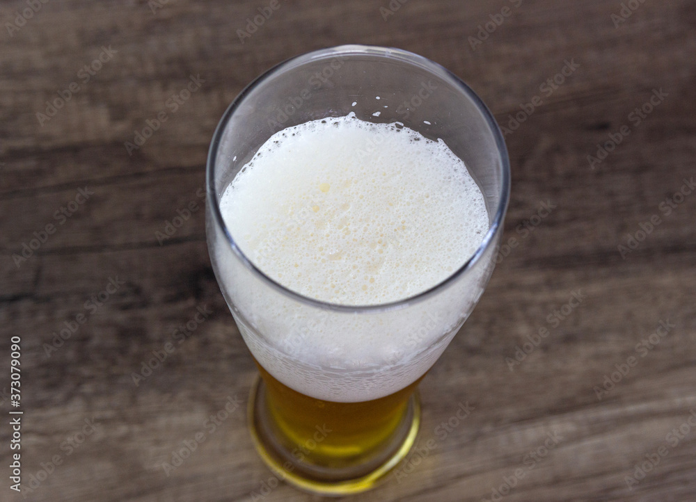 Full glass of beer, on a wooden table. Amber beer in a glass. Full glass of beer, on a wooden table. Amber beer in a glass.