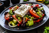 Fresh Greek salad - feta cheese, tomatoes, cucumber, red pepper, black olives and onion on wooden table
