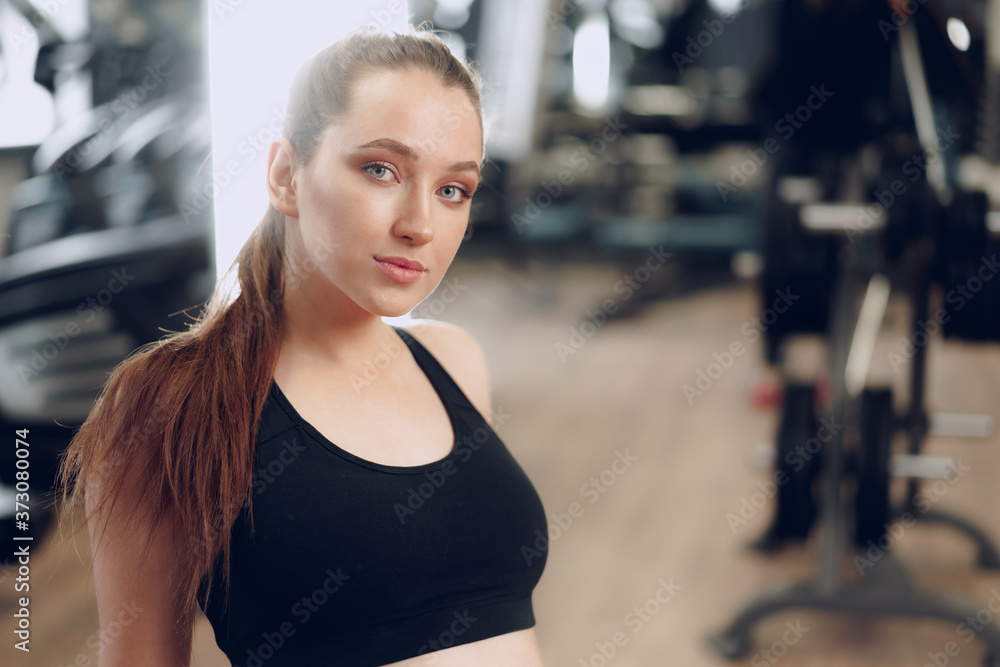 Brunette young woman sitting tired in a gym after workout