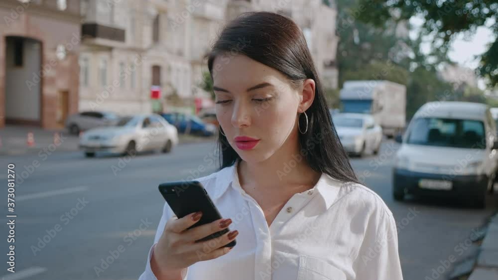 Attractive young woman using smartphone at city background. Attractive young woman using smartphone at city background.