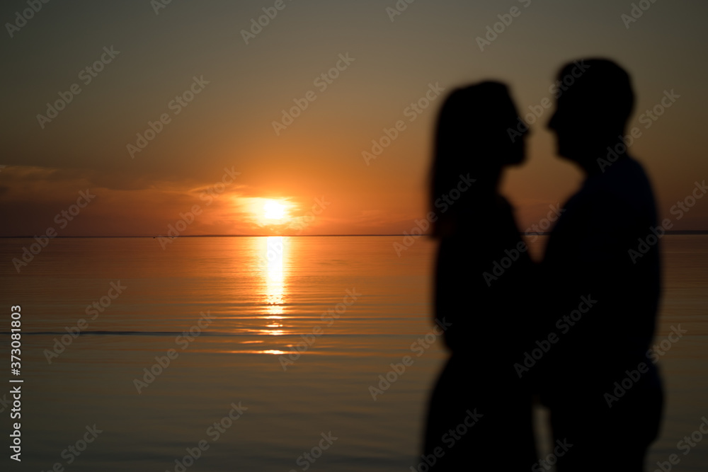 silhouette of couple on the beach. Beautiful sunset of bright red orange color. Background for the travel website screensaver. Romantic picture, the concept of love.