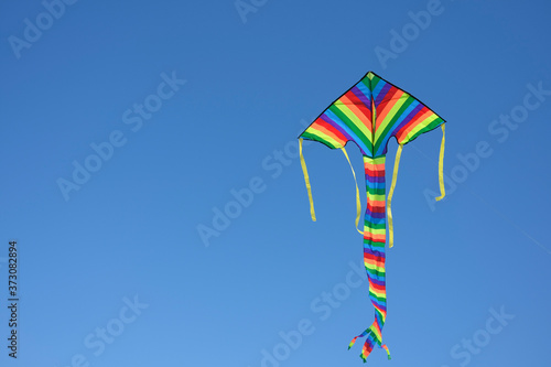 Flying multicoloured kite against clear blue sky