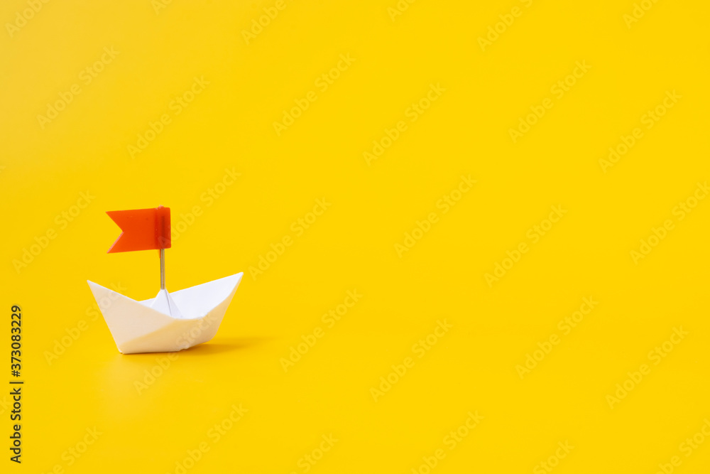 White paper boat with a red flag on a yellow background. Concept . White paper boat with a red flag on a yellow background. Concept .