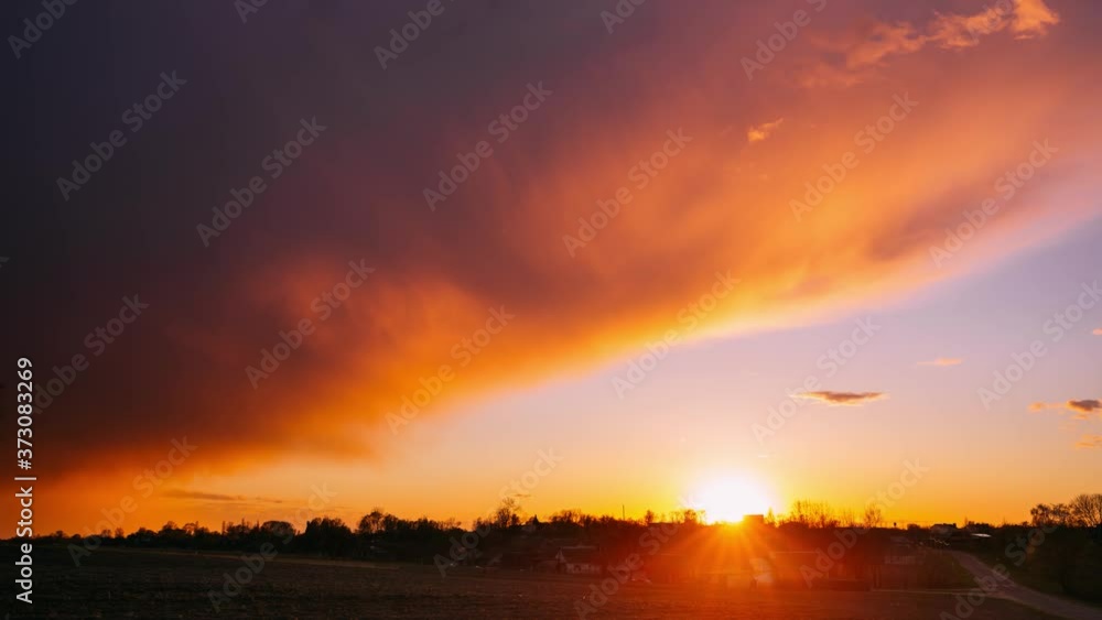 Sun Sunshine Through Sunset Sky. Bright Dramatic Sky With Fluffy Clouds. Yellow, Orange, Blue And Magenta Colours. Dawn Sky Sun Sunshine Through Sunset Sky. Bright Dramatic Sky With Fluffy Clouds. Yellow, Orange, Blue And Magenta Colours. Dawn Sky