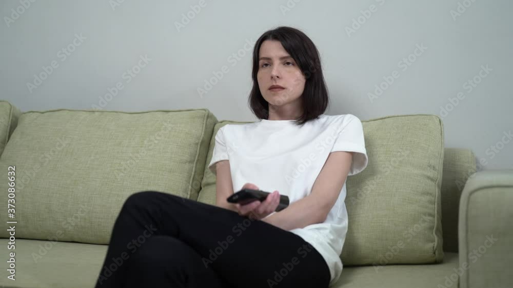 a woman with a remote control switches channels and laughs at the show a woman with a remote control switches channels and laughs at the show