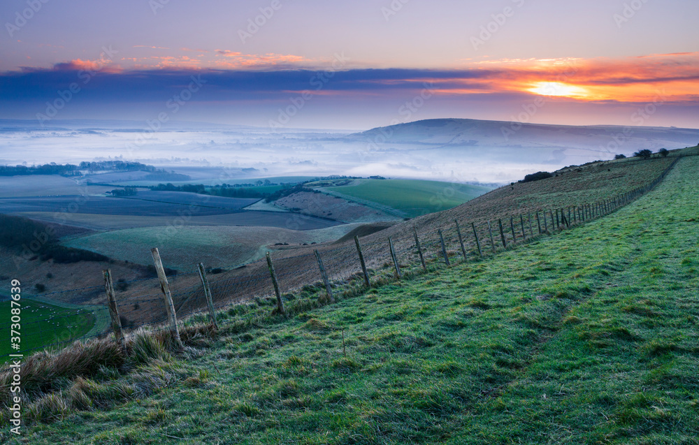 Dawn from Bo Peep on the south downs with the sun rising over the Wilmington hill and the Sussex Weald in East Sussex South east England mid February