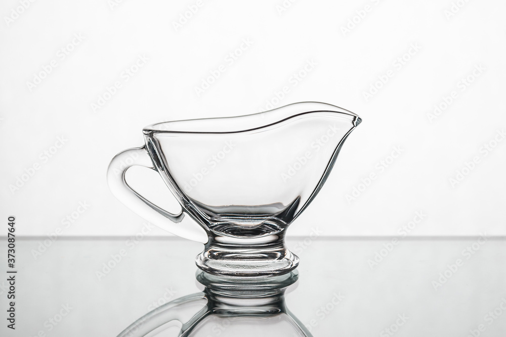 Empty clear glass gravy boat isolated on a white background Empty clear glass gravy boat isolated on a white background