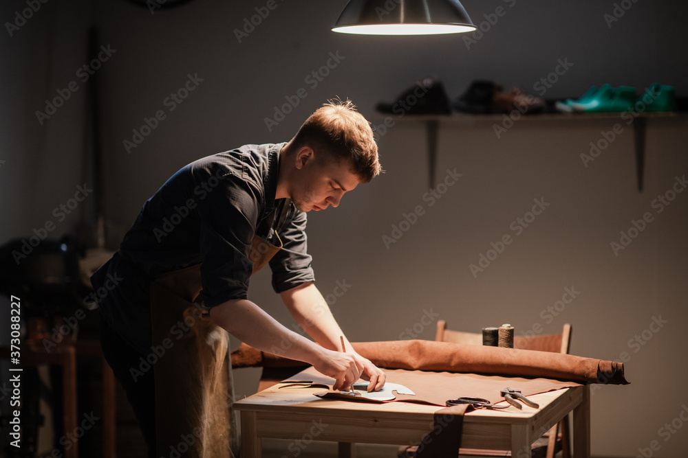 a young apprentice makes blanks for the production of shoes in the workshop. a young apprentice makes blanks for the production of shoes in the workshop.