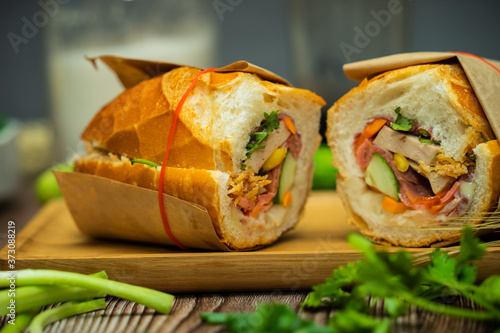 Snack at break time. Famous Vietnamese food is Banh mi thit and black coffee, popular street food from bread stuffed with raw material: pork, ham, pate, egg and fresh herbs.Typical Vietnamese sandwich photo