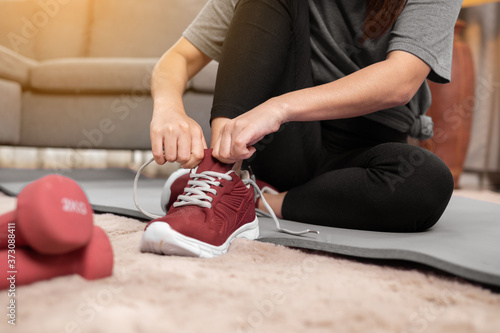 Close up woman putting on sport shoes in room. workout and exercise at home.