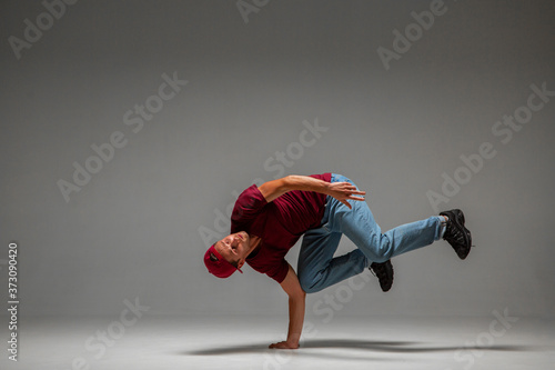 Cool guy breakdancer dancing lower break dance on the floor isolated on gray background. Break dance lessons