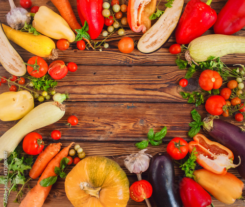 Frame of different vegetables around wooden table background. Autumn harvest. Free copy space in the center, top view