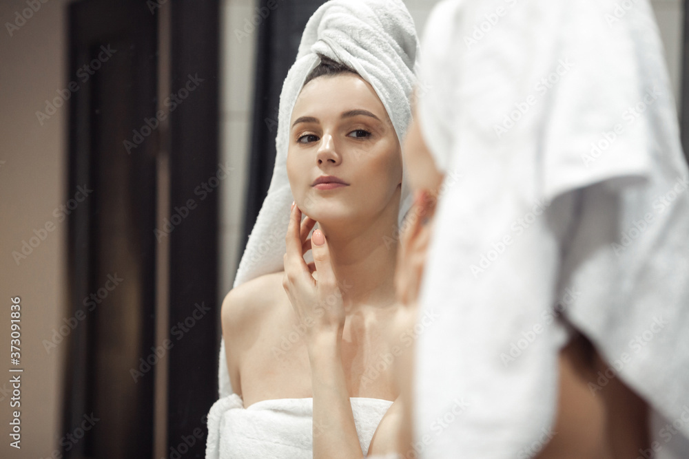 Young woman in bathroom behind mirror Young woman in bathroom behind mirror