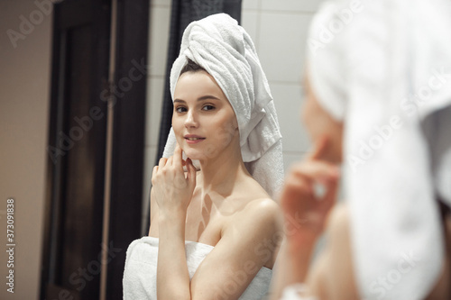 Young woman in bathroom behind mirror