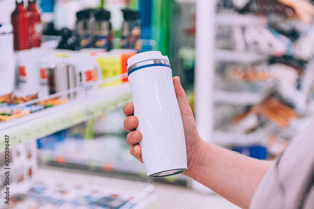 The guy in the supermarket holds a thermos in his hands.