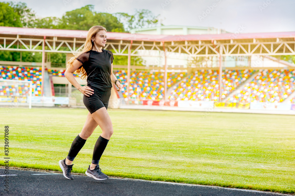 Fitness woman on stadium runs at sportwear