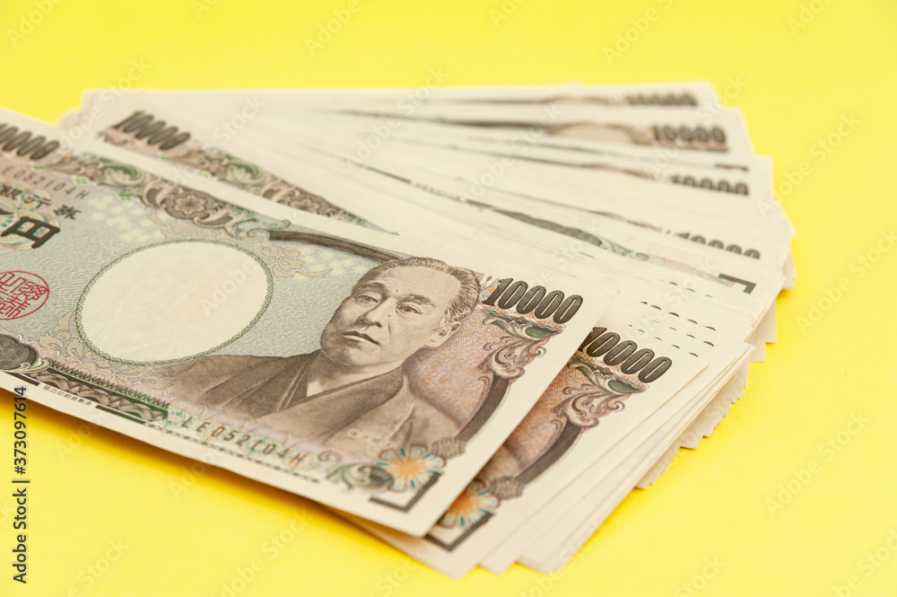 Ten thousand yen (10,000 yen) banknotes stacked. Japanese money. Paper money. Isolated on yellow background. Top view
