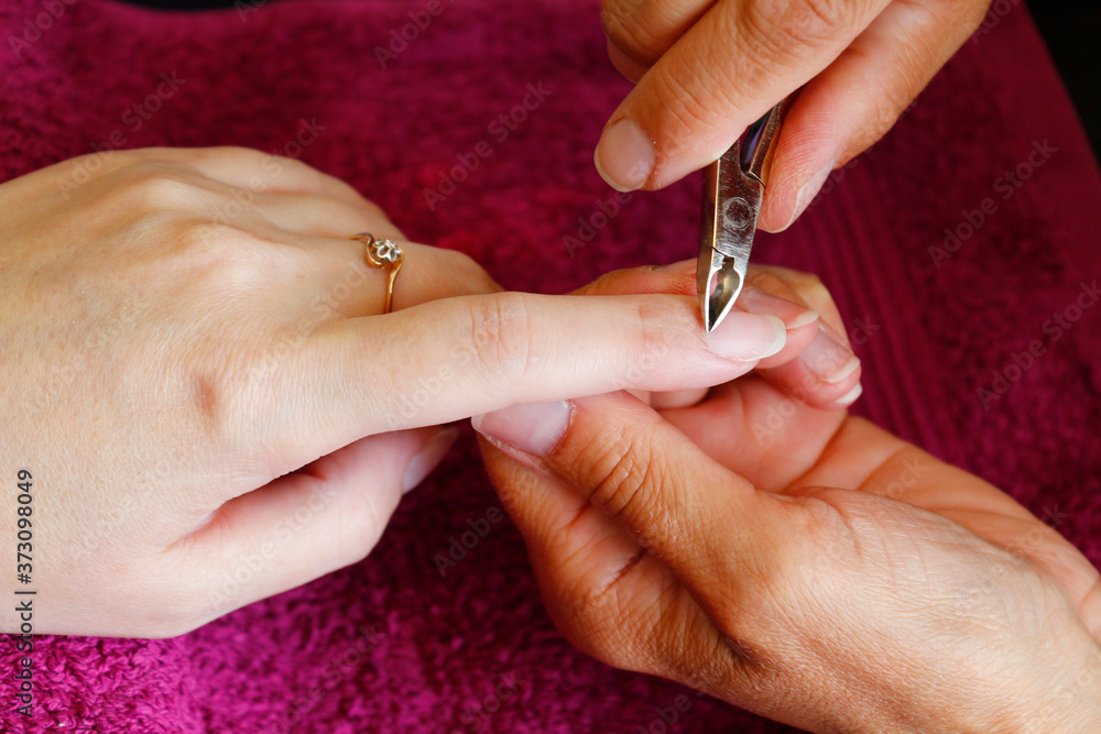 Manicurist working with clients nails at table, close up. Healthy, well groomed nails, natural beauty. Selective focus.