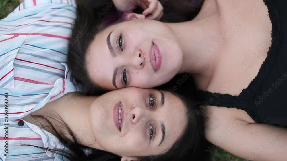 Girlfriends smiling to camera on grass outdoors Girlfriends smiling to camera on grass outdoors