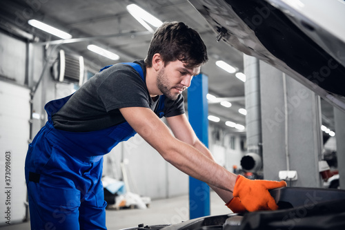 Mechanic inspects the engine under the car hood