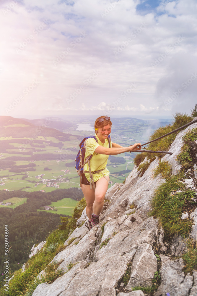 Naklejka premium Adventure in the mountains. Young tourist girl is climbing on rocky mountain in Austria