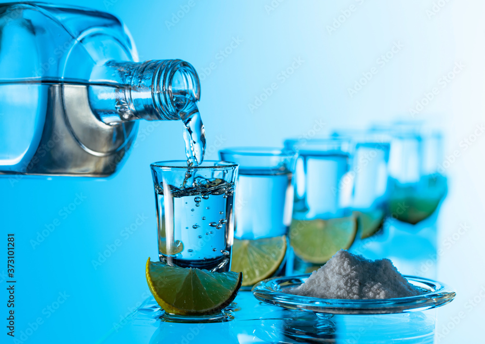 Tequila, salt and lime slices on a blue background. Tequila, salt and lime slices on a blue background.
