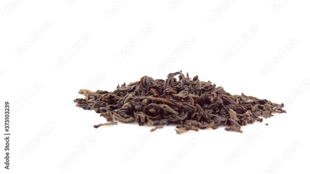Dried black tea leaves rotate on a plate. Close-up of a rotation of large leaf black tea on a white background. A handful of large leaf black tea rotates on a white plate. Dried black tea leaves rotate on a plate. Close-up of a rotation of large leaf black tea on a white background. A handful of large leaf black tea rotates on a white plate.