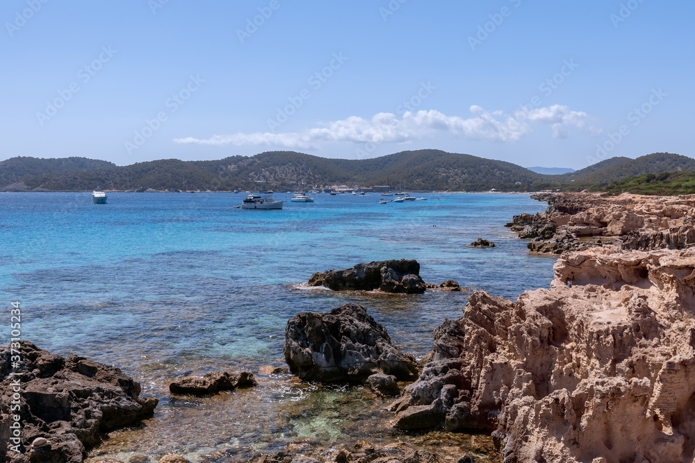 View of the beautiful rocky coast turquoise sea with boats. Ibiza. Balearic Islands, Spain