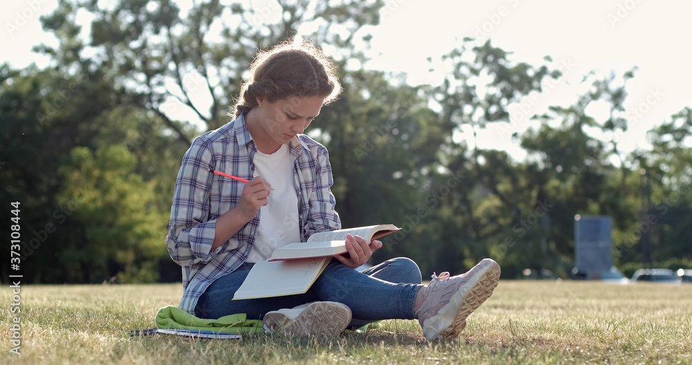 A student prepares for college by writing in a notebook in pencil A student prepares for college by writing in a notebook in pencil