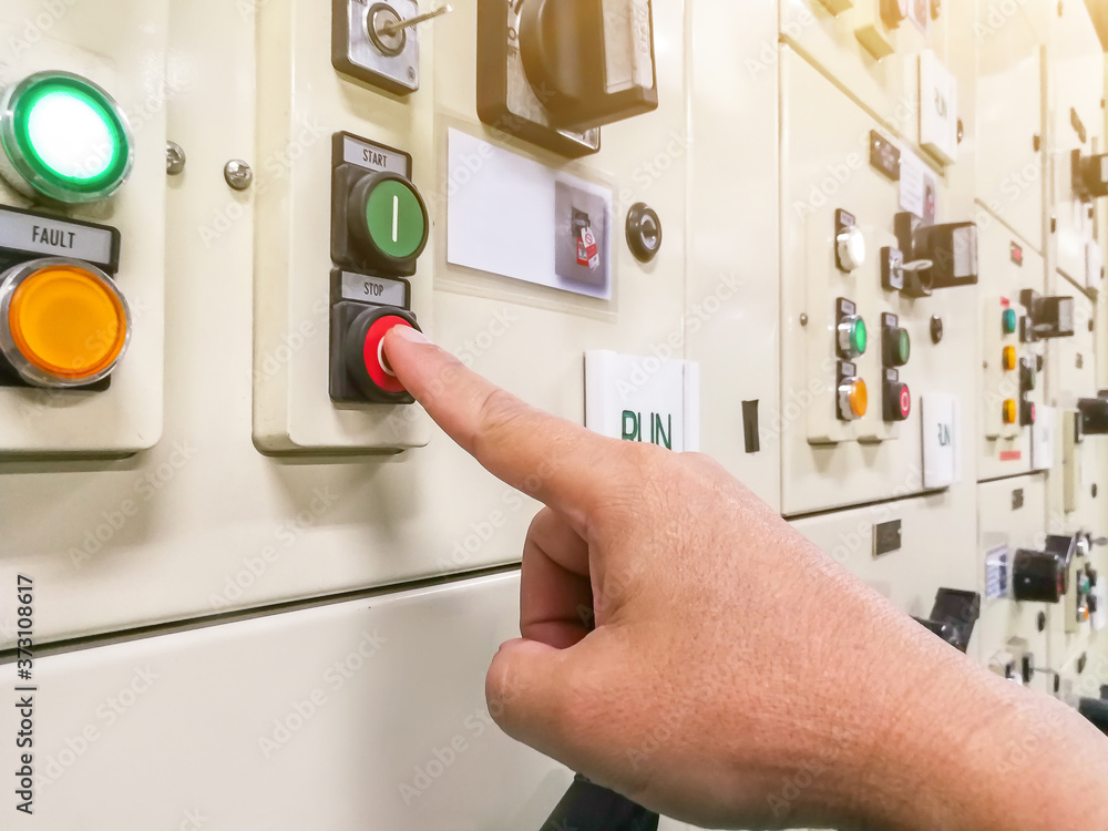 Hand holding the control panel of the industrial plant and pushing or