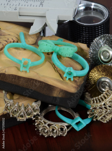 Rubber molds, green wax, various types of silver metal molds and equipment used in the production of jewelry, very placed on a wooden table.